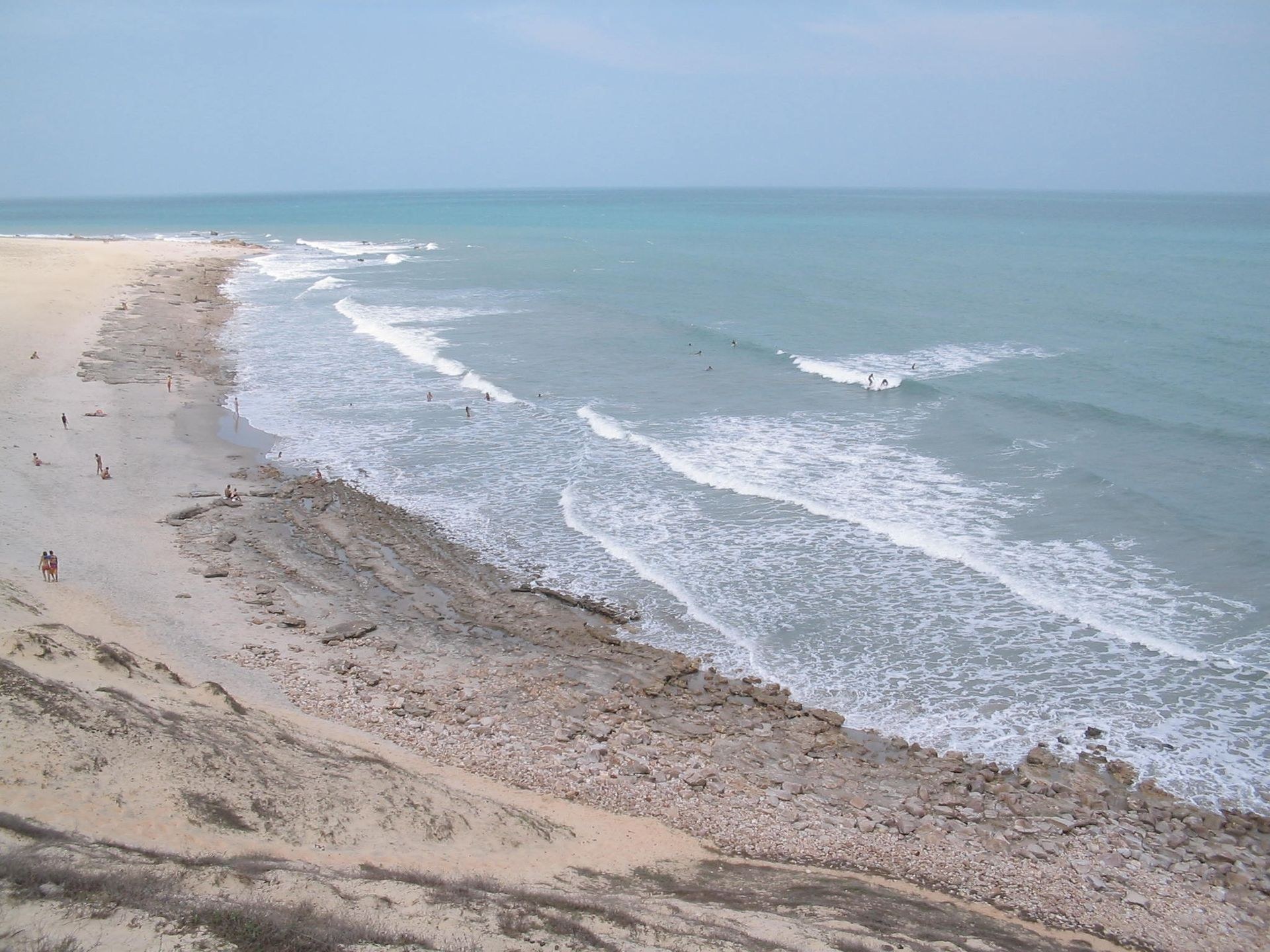 Costa com recifes, faixa de areia e mar turquesa vista de cima em Jericoacoara, Ceará.